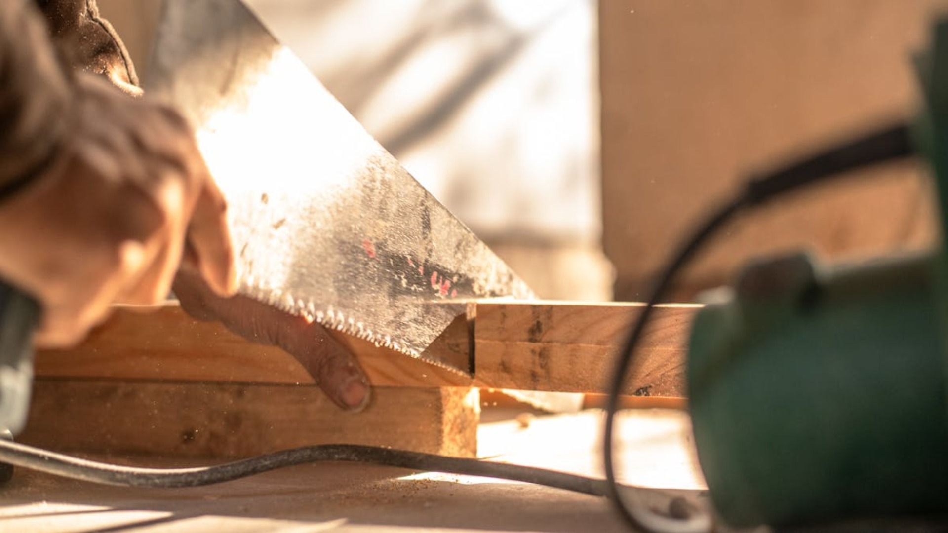 Persona cortando madera con una sierra de mano; vista de cerca.