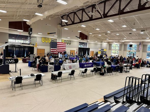 A large room with tables and chairs and a large american flag on the wall.