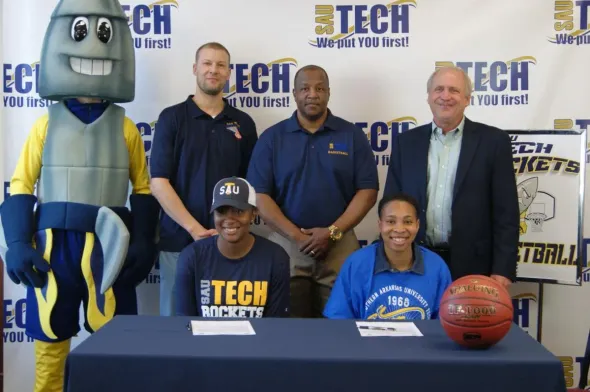 A group of people standing around a table with a basketball on it