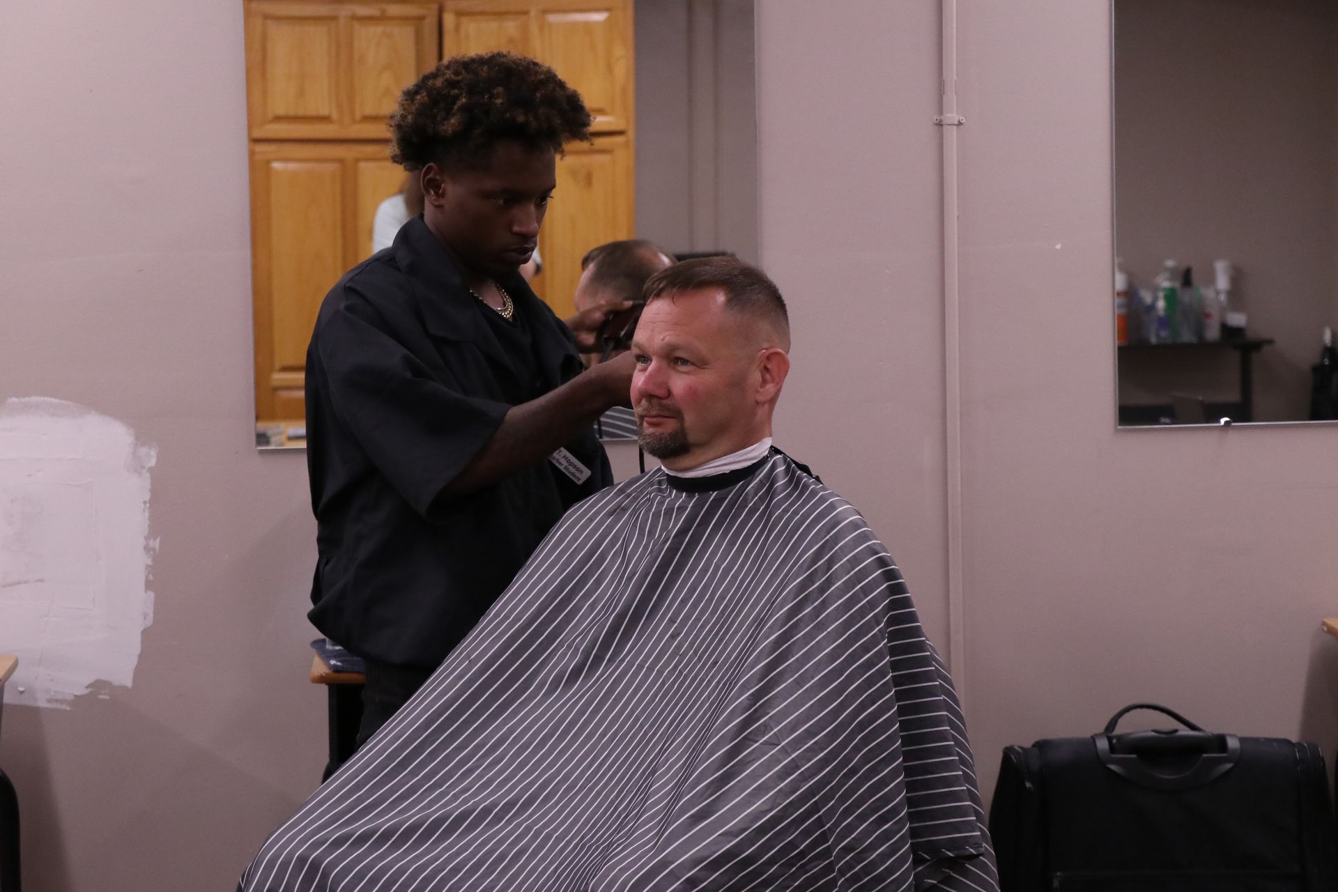 A man is getting his hair cut by a barber in a barber shop.