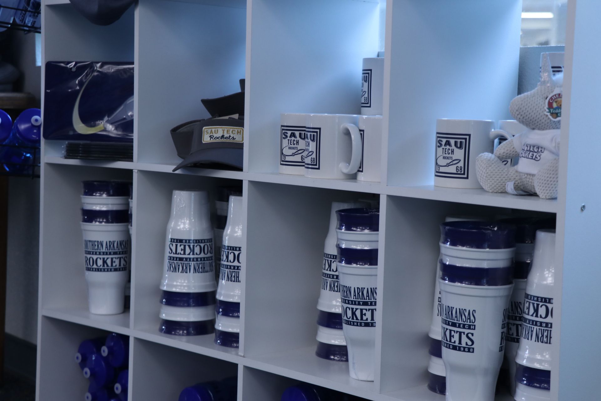 A shelf filled with cups and a teddy bear