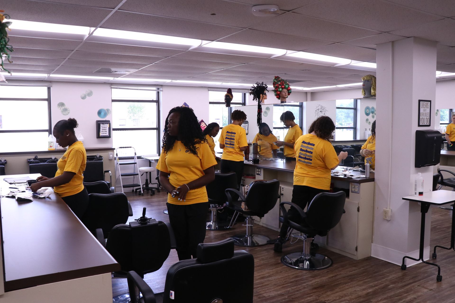 A group of women in yellow shirts are working in a salon.
