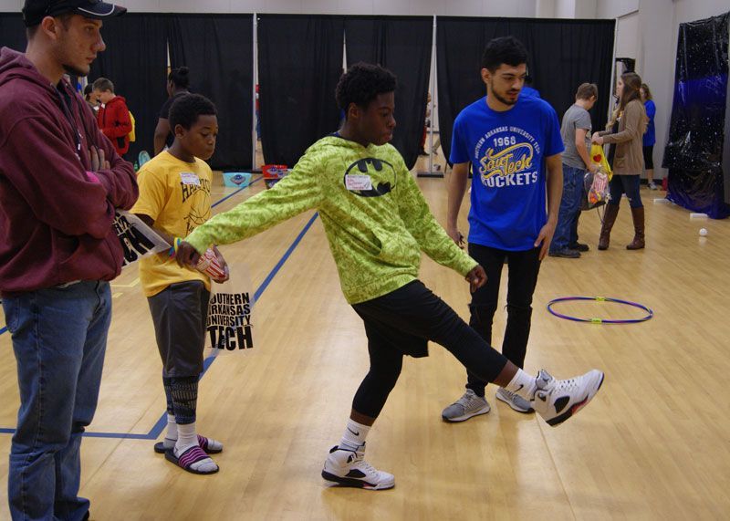 A boy wearing a blue shirt that says bears is kicking a ball