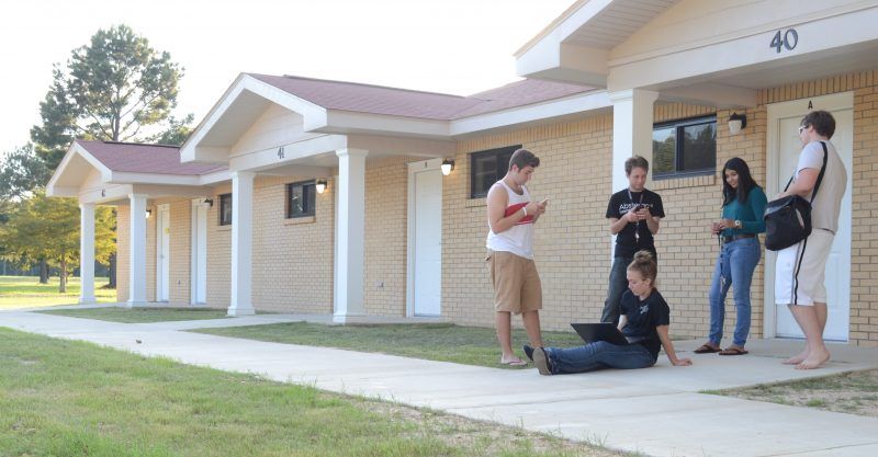 A group of people are standing outside of a row of houses.