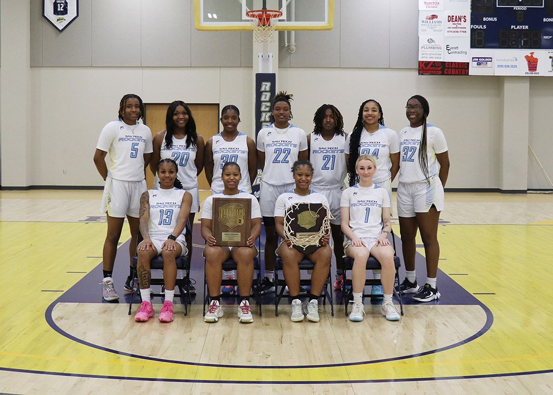 A group of women are posing for a picture on a basketball court.