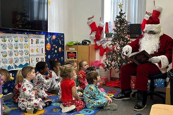 Santa claus is reading a book to a group of children.