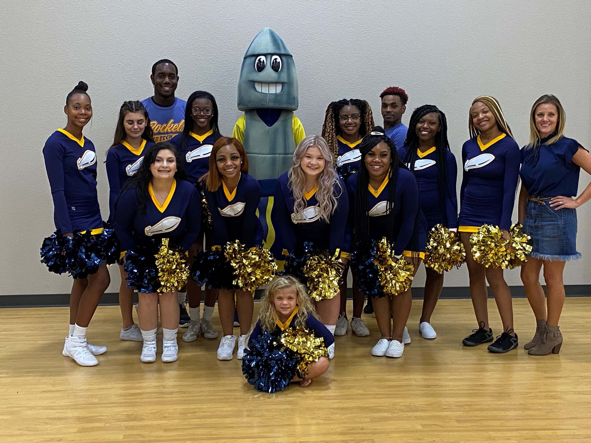 A group of cheerleaders are posing for a picture with a robot mascot.