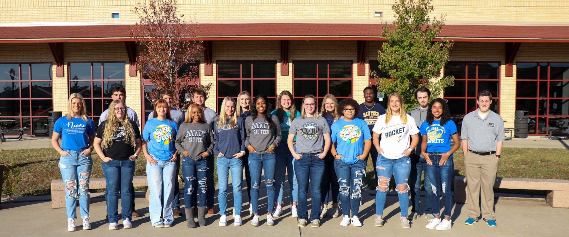 A group of young people are posing for a picture in front of a building.