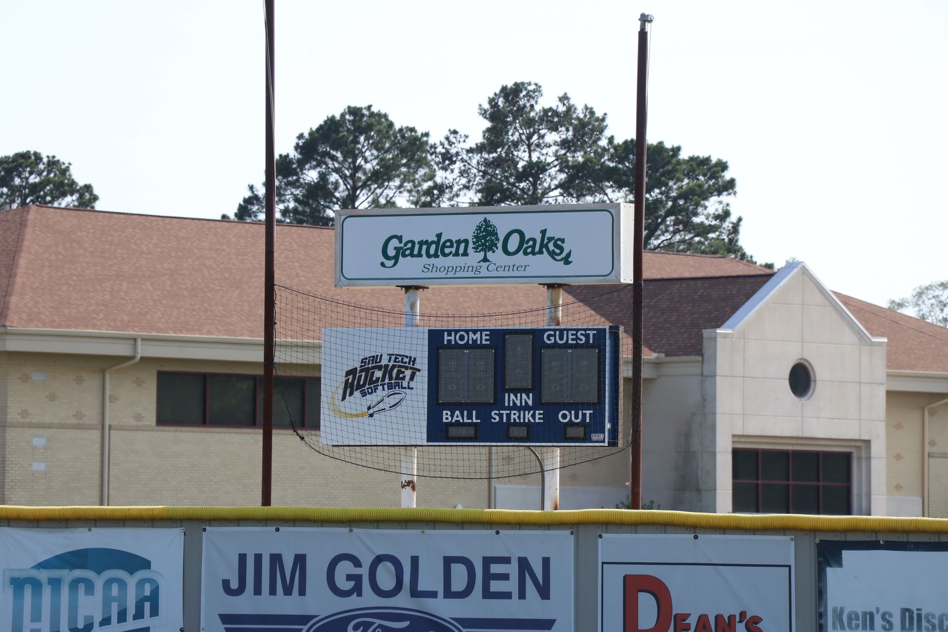 A baseball field with a scoreboard that says garden oaks