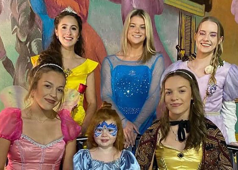 A group of young women dressed as princesses are posing for a picture.