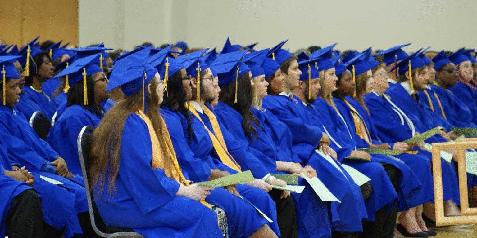 A large group of graduates are sitting in chairs at a graduation ceremony.