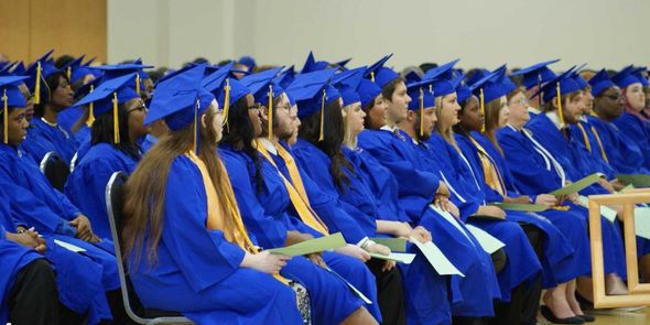 A large group of graduates are sitting in chairs at a graduation ceremony.