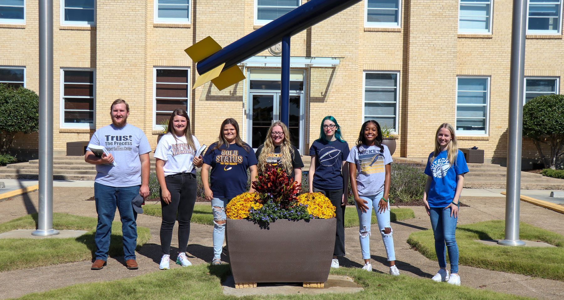 A group of people are posing for a picture in front of a building.
