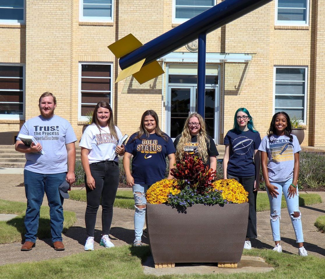 A group of people are posing for a picture in front of a building.