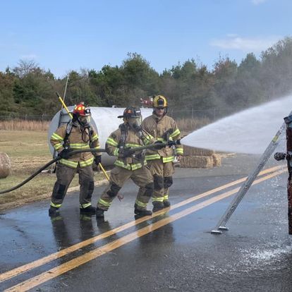 A group of firefighters are spraying water on a road.