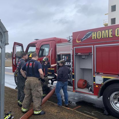 A group of firefighters are standing next to a fire truck.