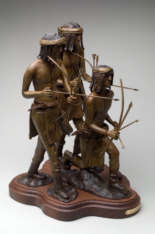 A bronze statue of three native americans holding bows and arrows