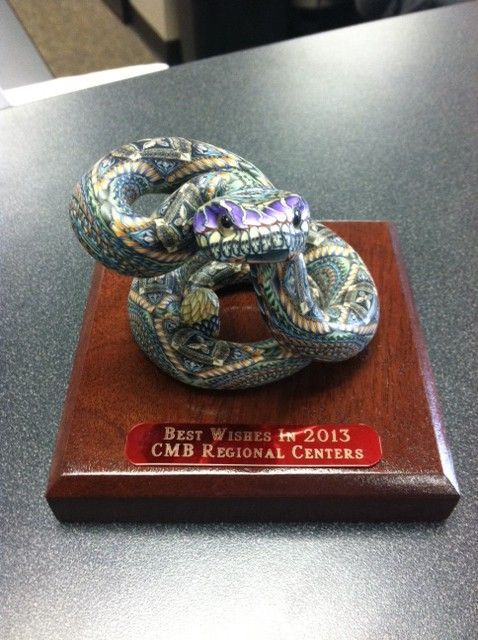 A statue of a snake on a wooden plaque that says best winner 2013 cmb regional centers