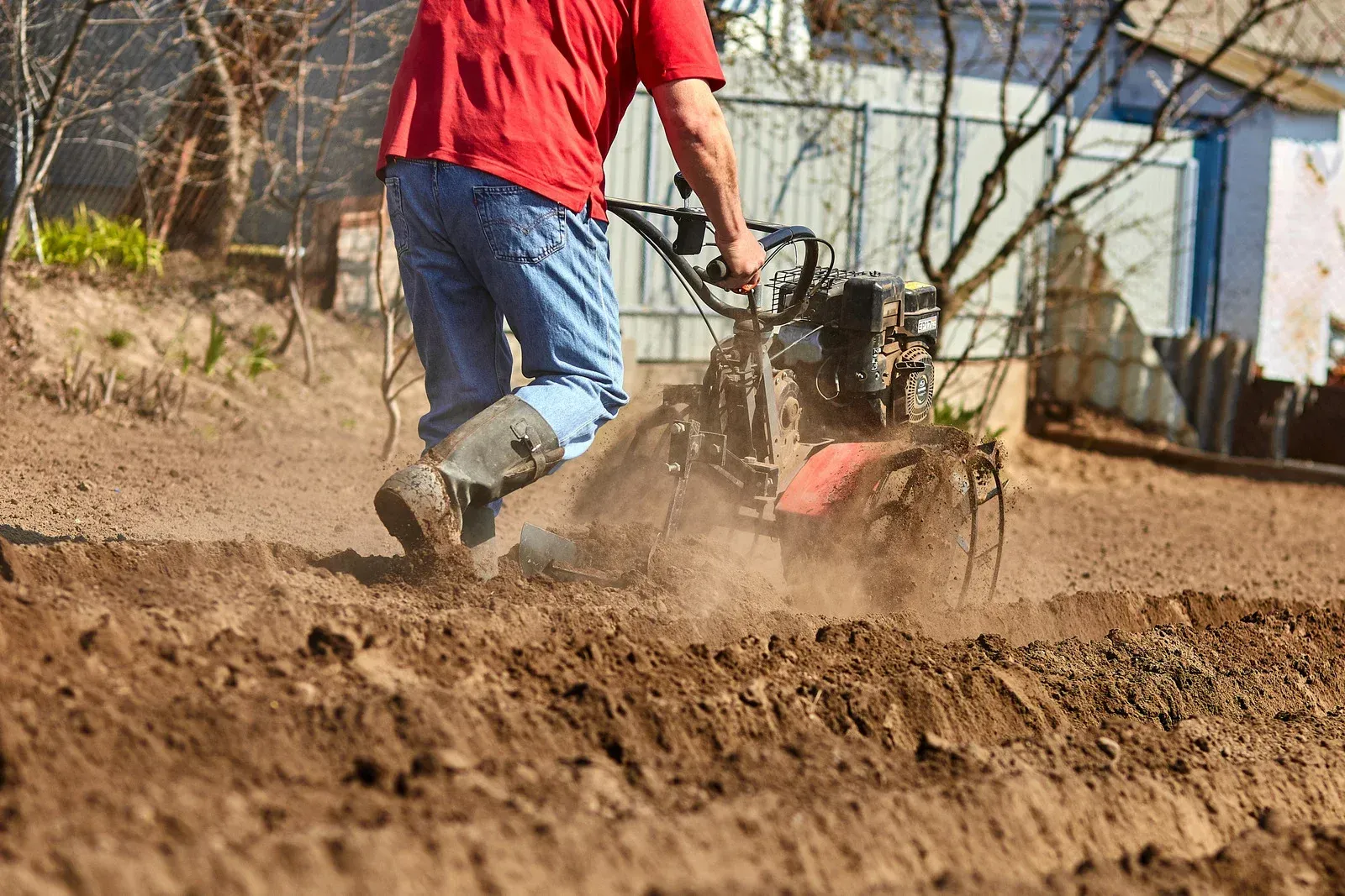 A man is fixing a hose in the dirt.