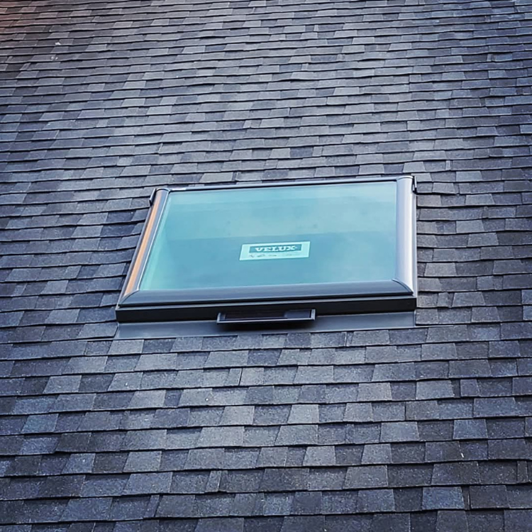 A skylight on top of a shingle roof
