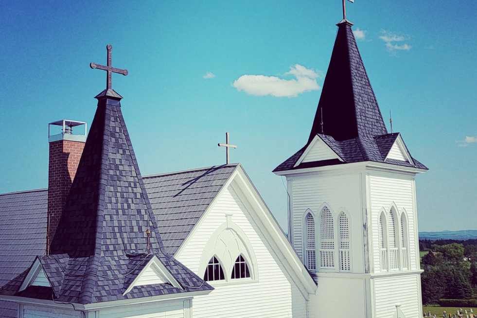 A white church with two towers and a cross on top.