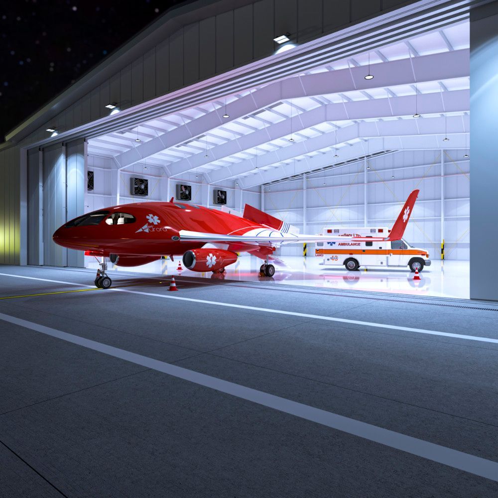 Red airplane and medical transport vehicle inside a brightly lit hangar at night.