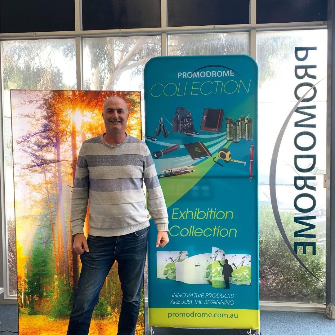 A man standing in front of a sign that says exhibition collection