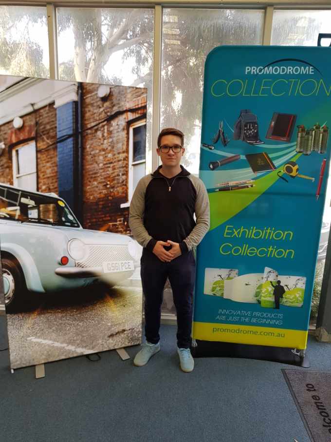 A man is standing in front of a sign that says exhibition collection.