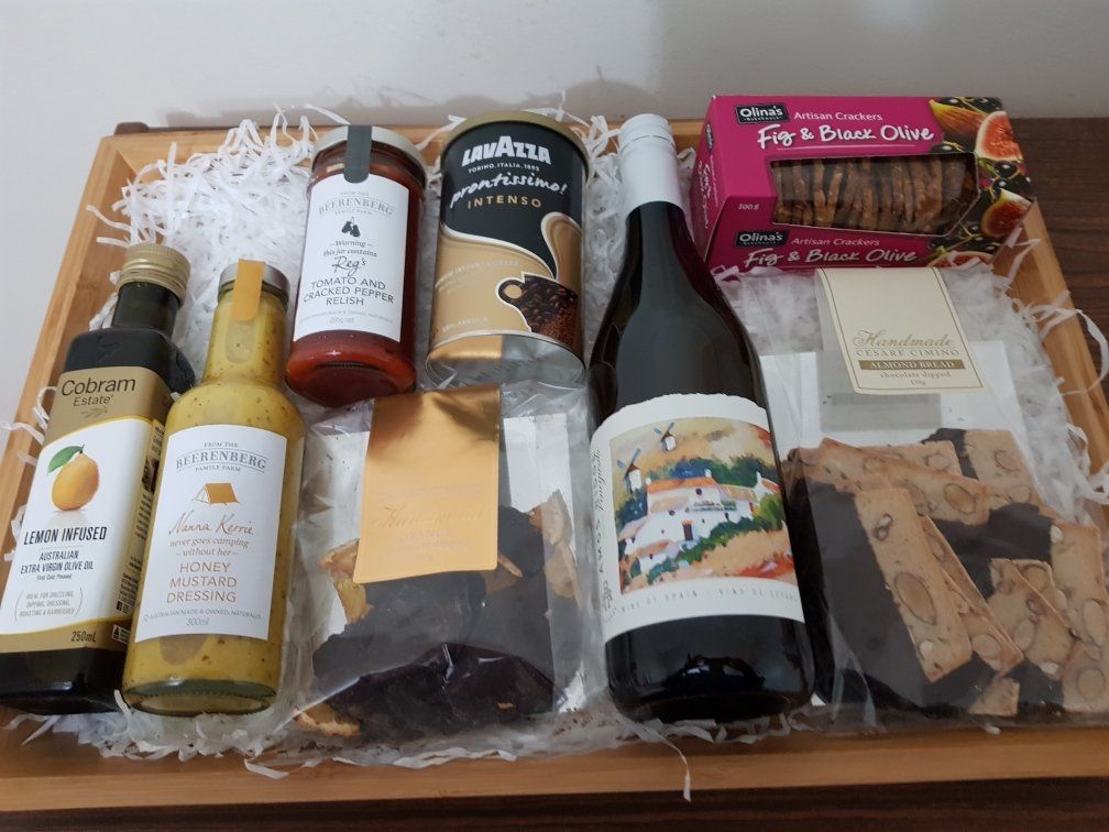 A wooden tray filled with bottles of wine and other food items