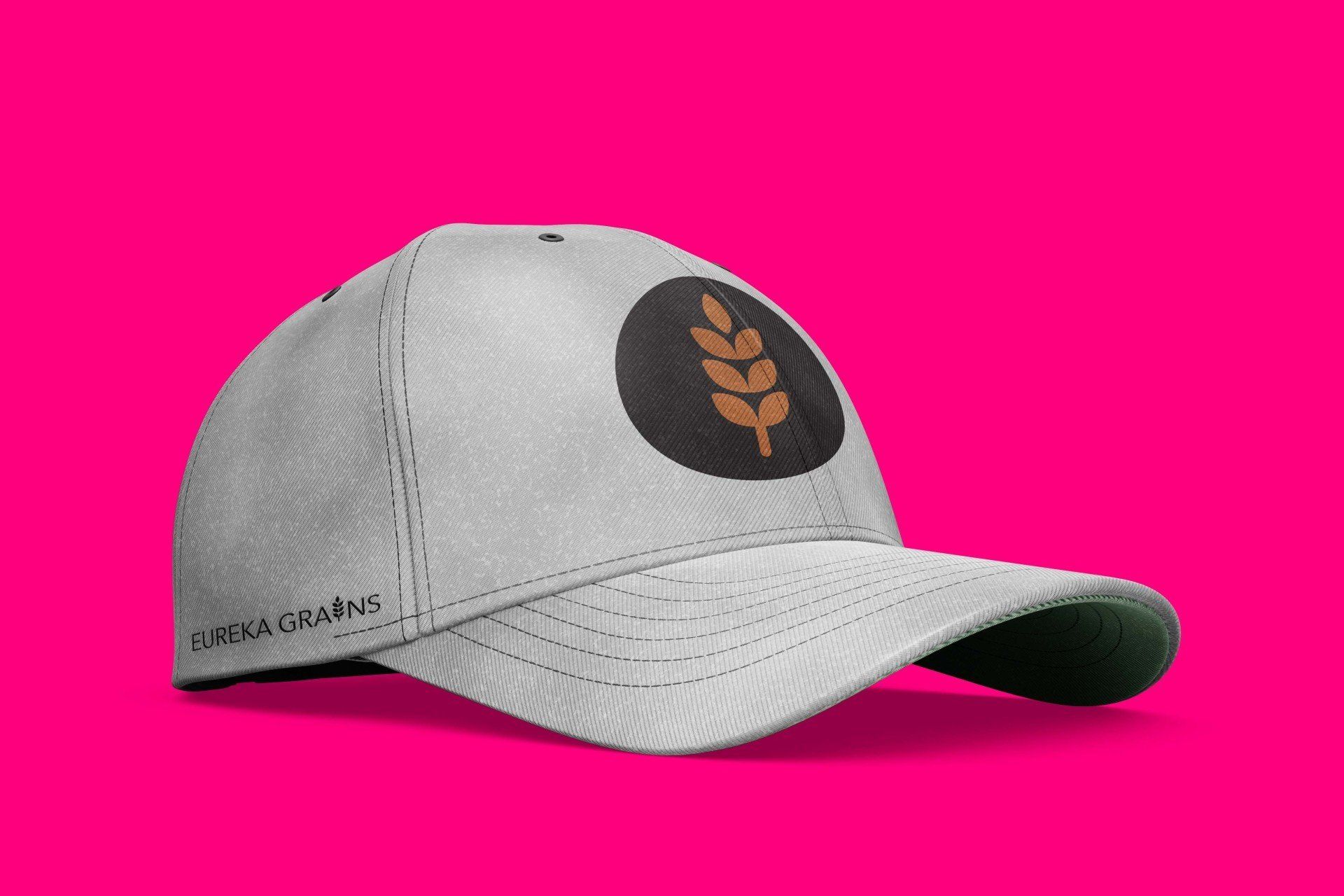 A baseball cap with a wheat ear on it is on a pink background.