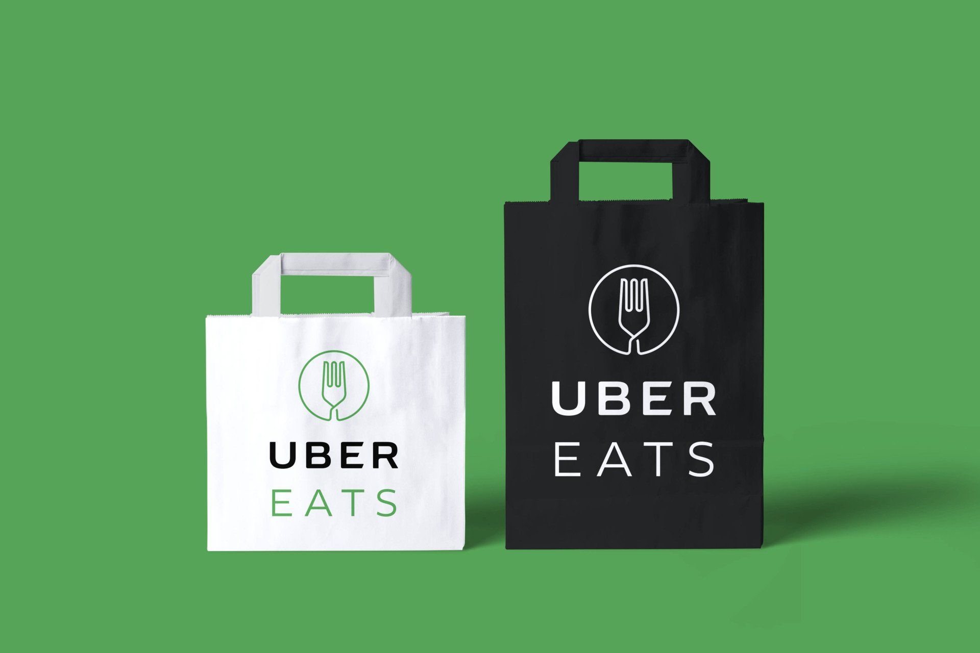 Two uber eats bags are sitting next to each other on a green background.