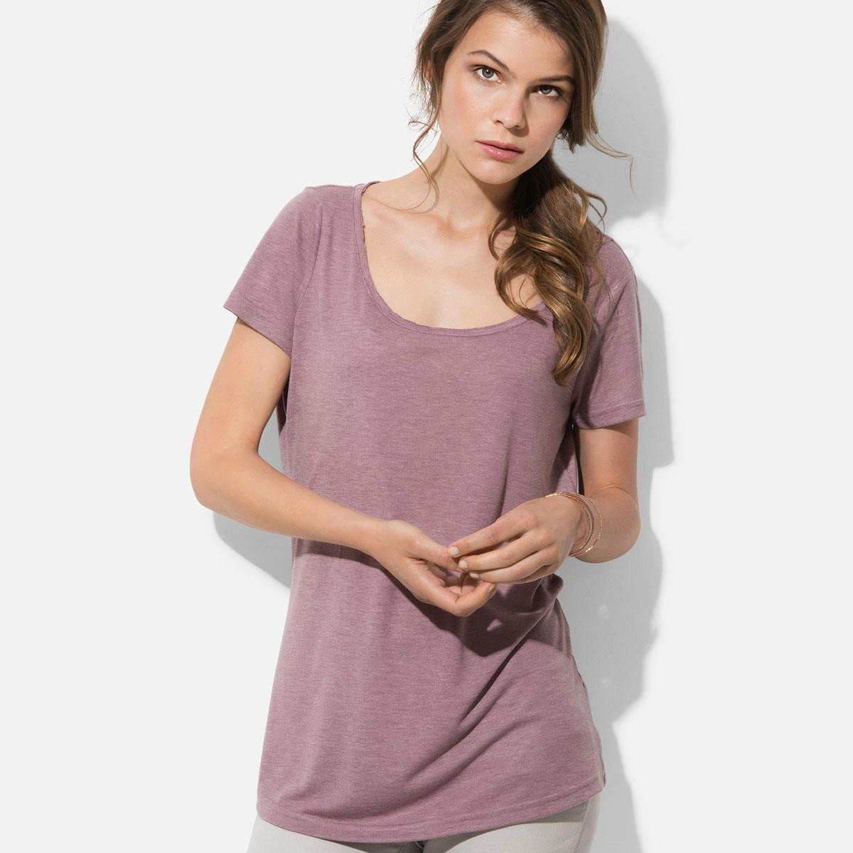 A woman in a purple shirt is standing in front of a white wall