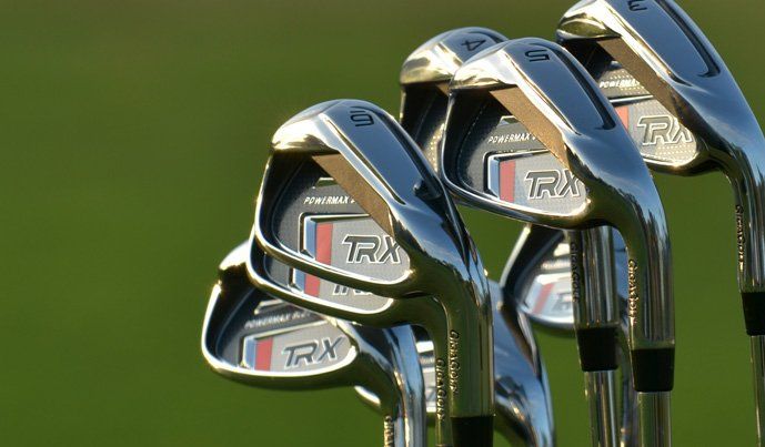 A row of golf clubs are lined up on a green field.
