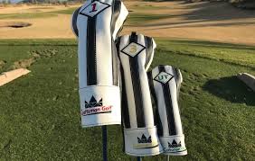 Three golf club covers are sitting on top of a golf course.
