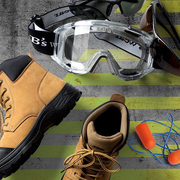 A pair of b 's work boots are surrounded by goggles sunglasses and ear plugs