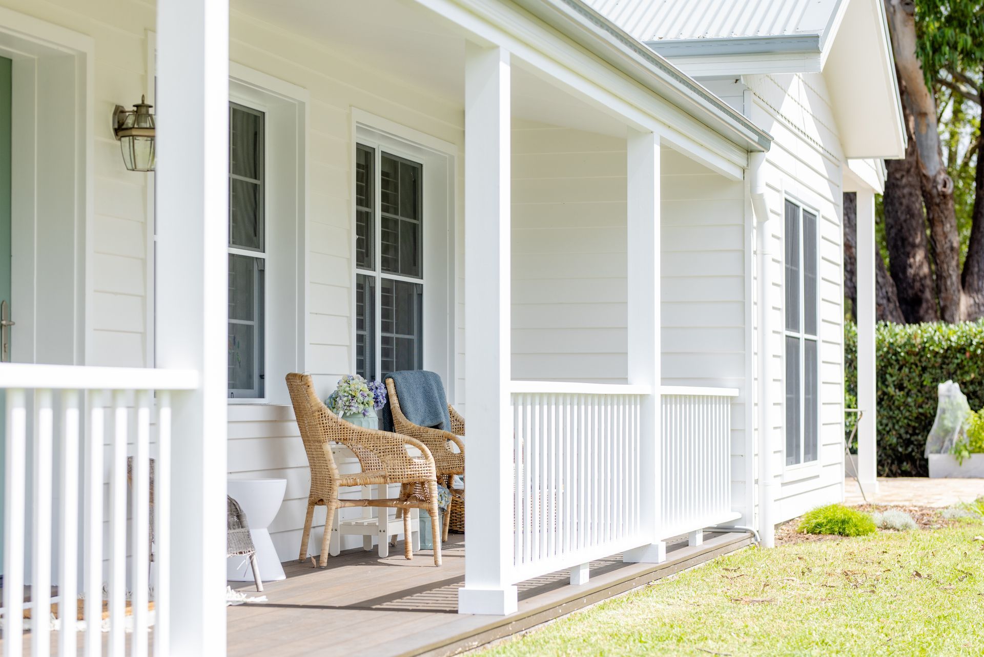 White porch with wicker chairs, white railings, windows, and green grass — Stark Building & Constructions In Berry, NSW