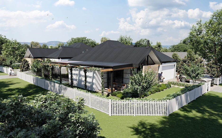 A modern house with a white picket fence, greenery, and dark roof under a cloudy sky  — Stark Building & Constructions In Berry, NSW