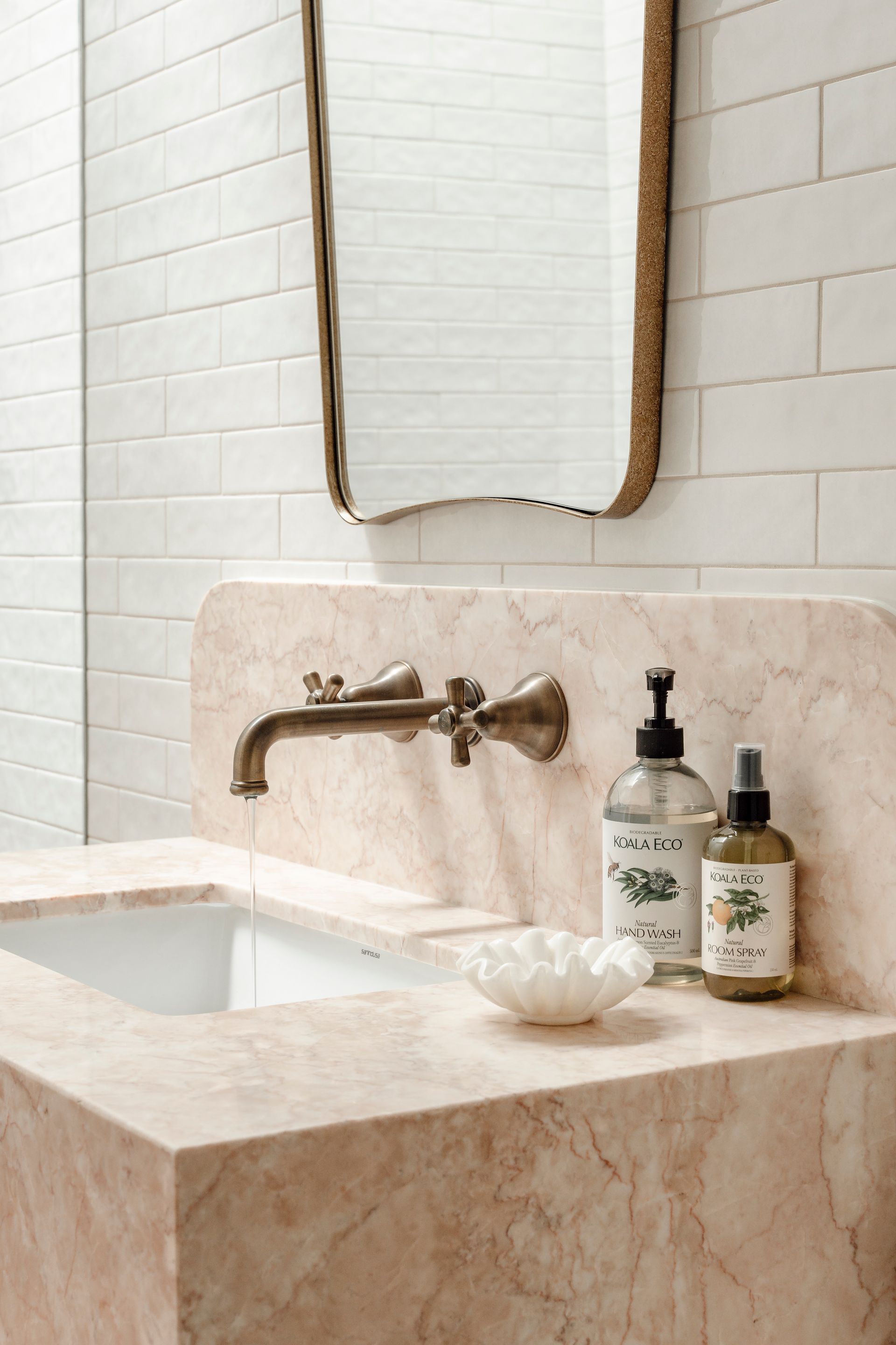 Pink marble sink with bronze faucet, mirror, and toiletries in a bathroom — Stark Building & Constructions In Berry, NSW