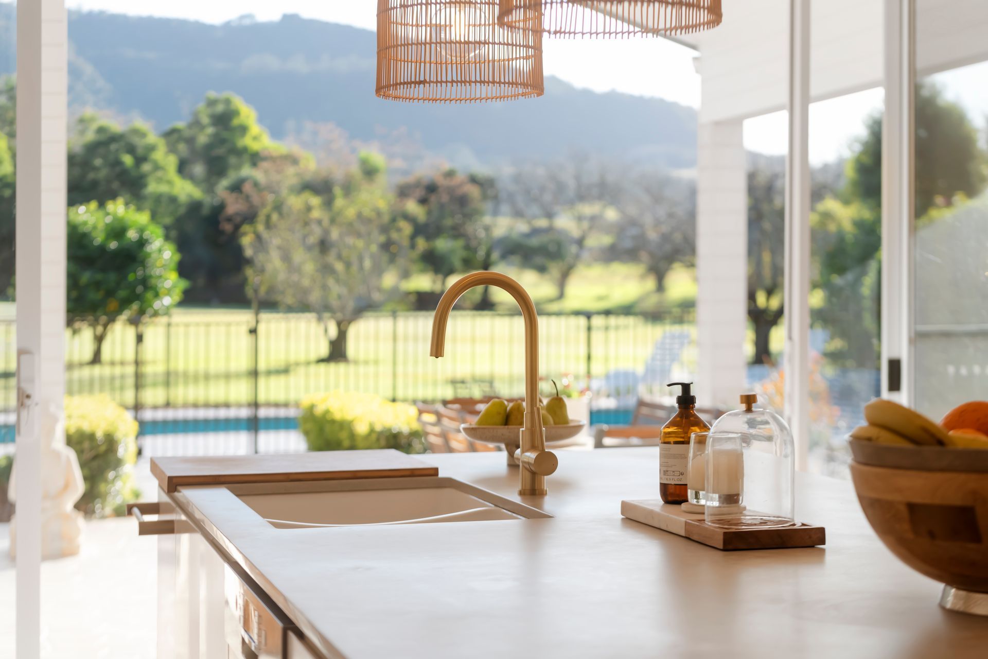 Kitchen island with gold faucet and open view of a green lawn and trees — Stark Building & Constructions In Berry, NSW