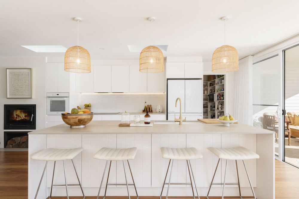 Modern White Kitchen With Island, Bar Stools, and Woven Pendant Lights — Stark Building & Constructions In Berry, NSW