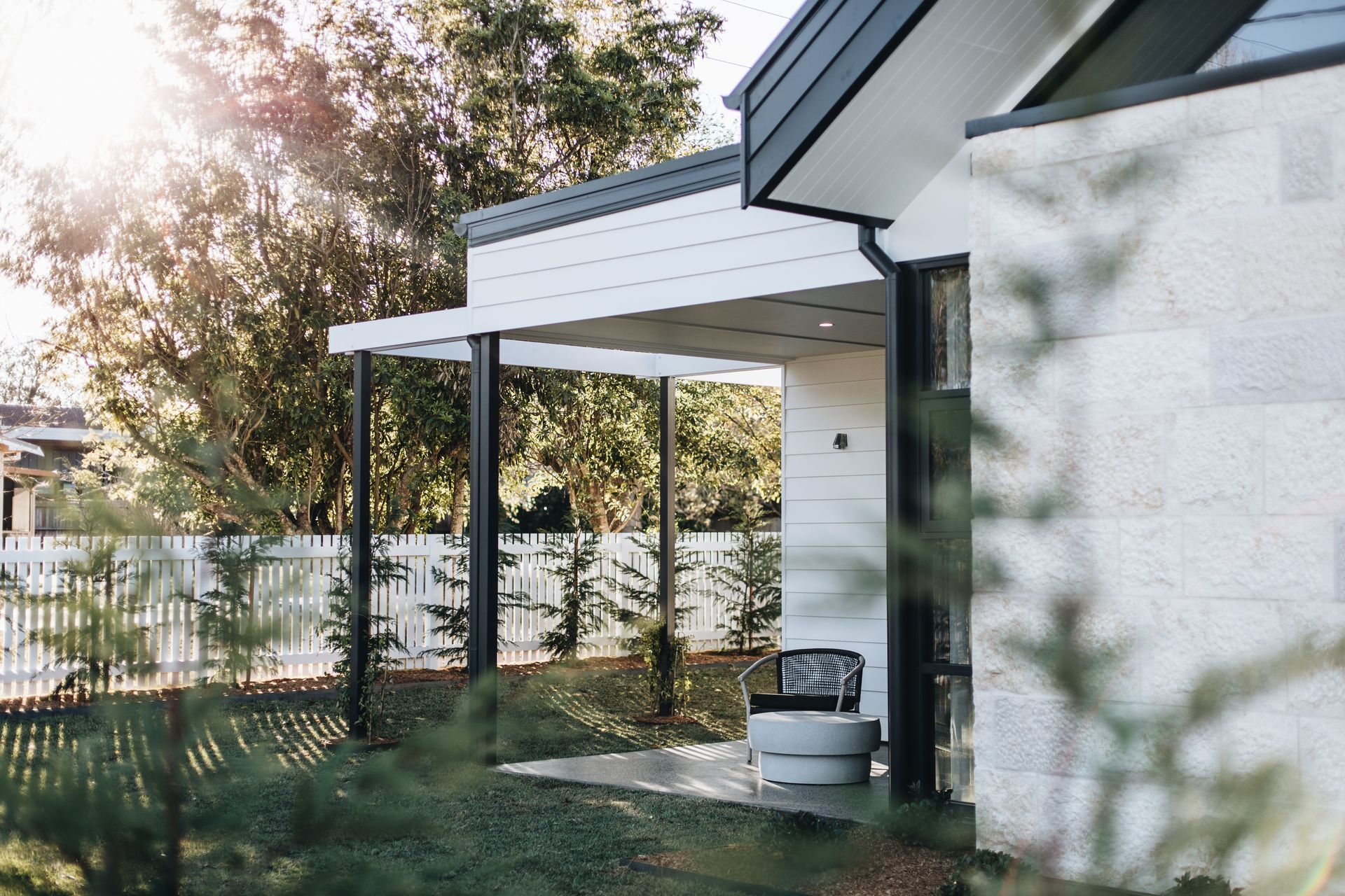 Modern home exterior with porch, white picket fence, and sunlight  — Stark Building & Constructions In Shoalhaven, NSW