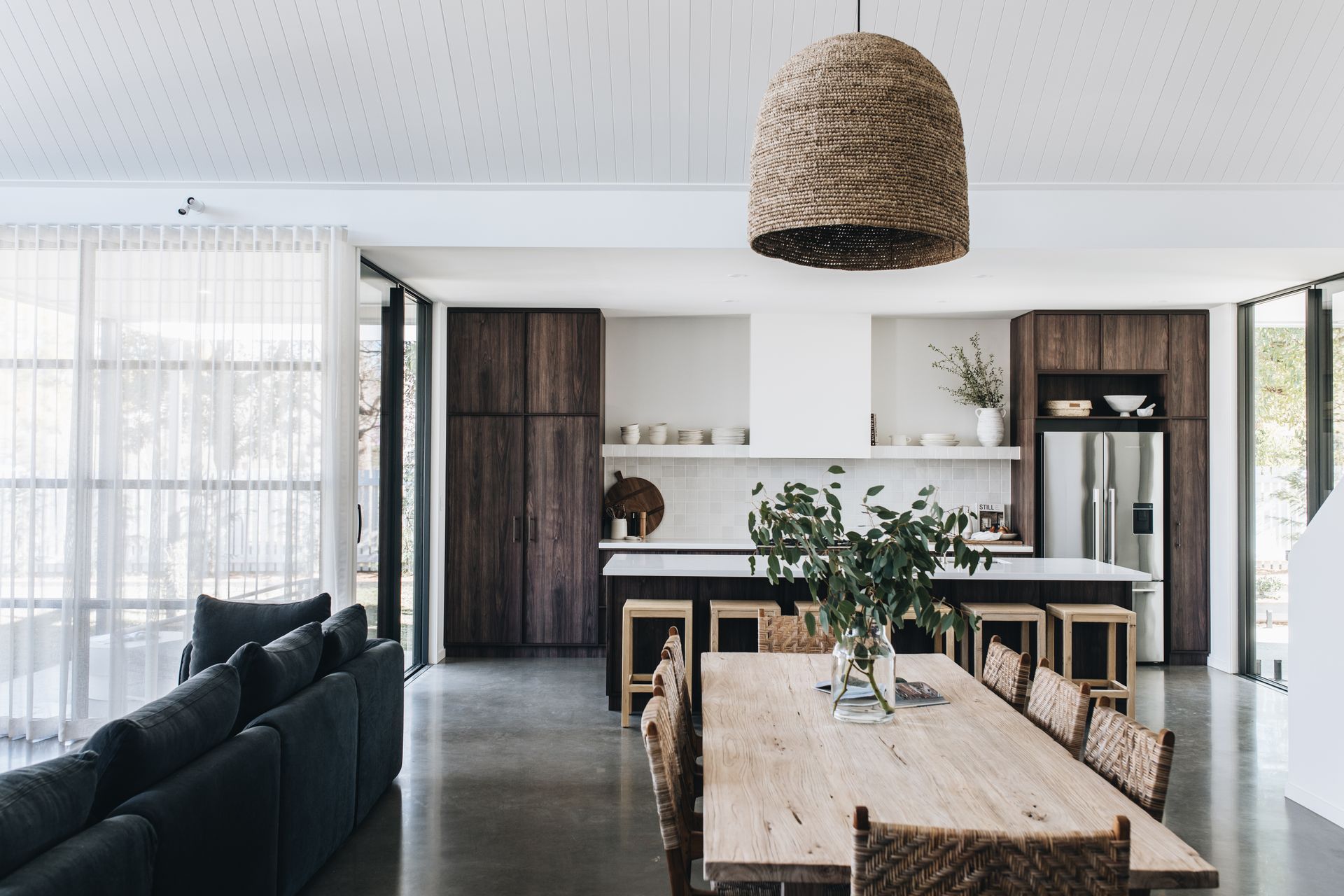 Spacious, modern kitchen and dining room with dark wood cabinets, light walls, and a long wooden table — Stark Building & Constructions In Shoalhaven, NSW
