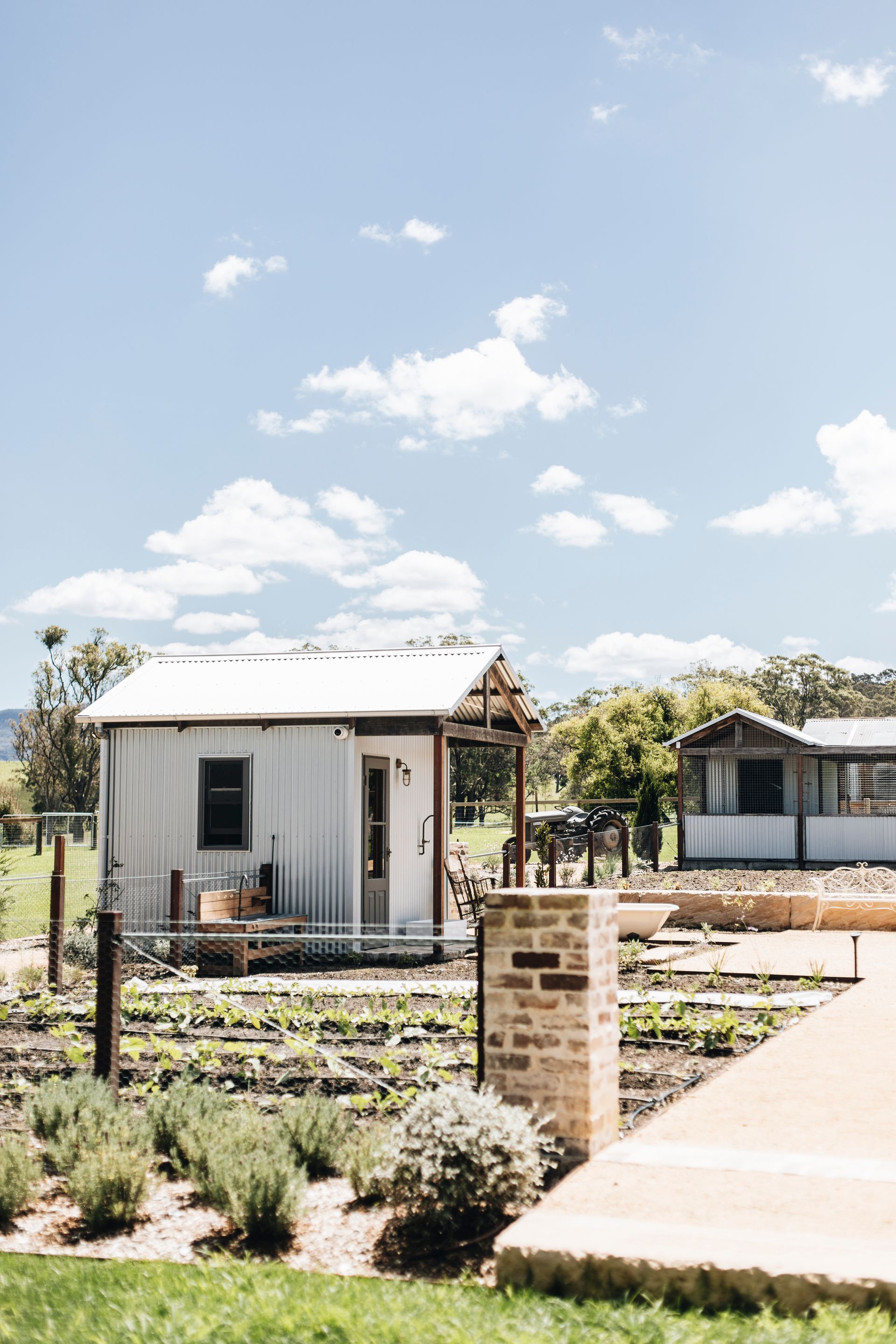 White metal cabin with small window on sunny day, brick mailbox in foreground, and other buildings in the background — Stark Building & Constructions In Berry, NSW