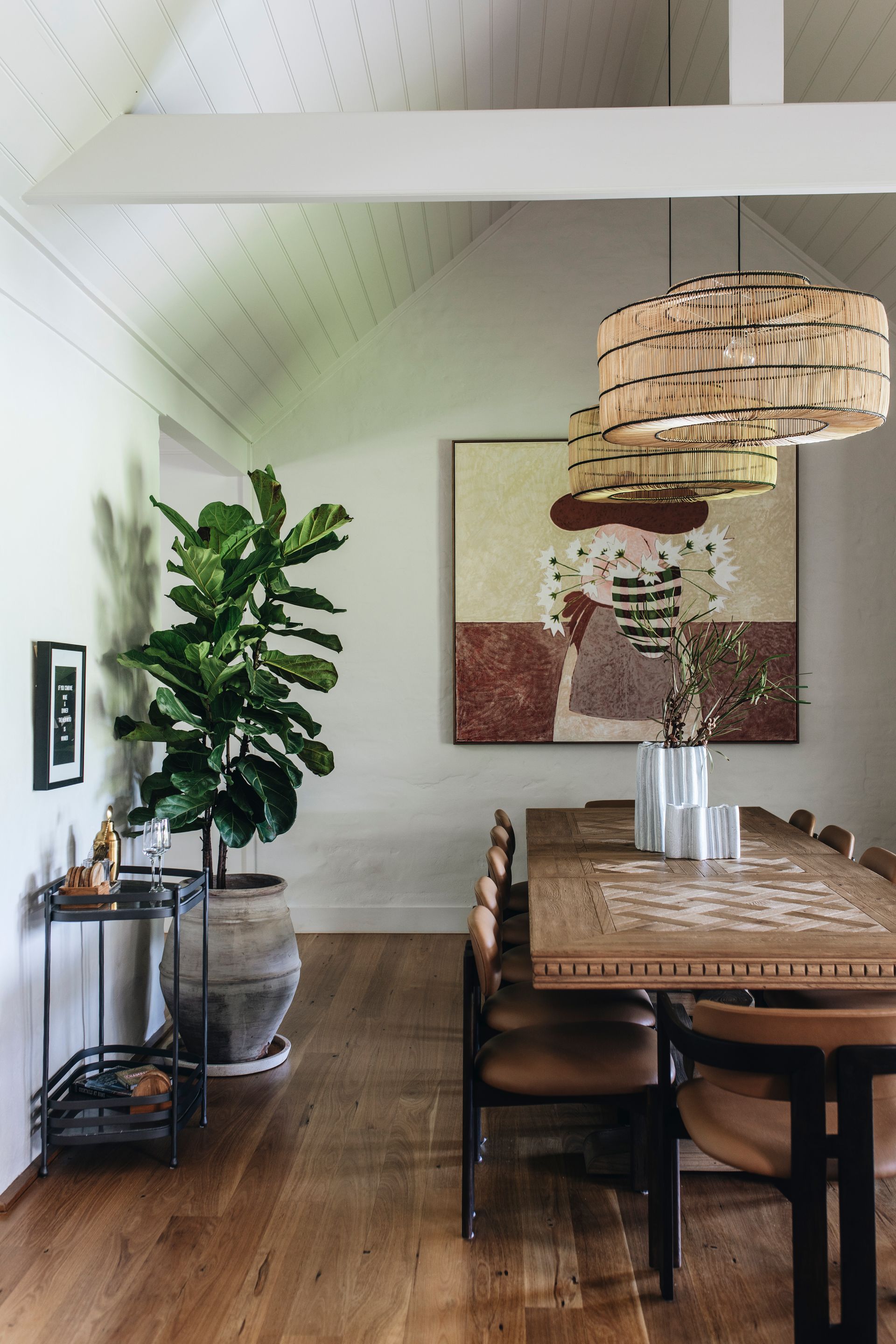 Dining room with wooden table, brown chairs, artwork, and a large plant — Stark Building & Constructions In Berry, NSW