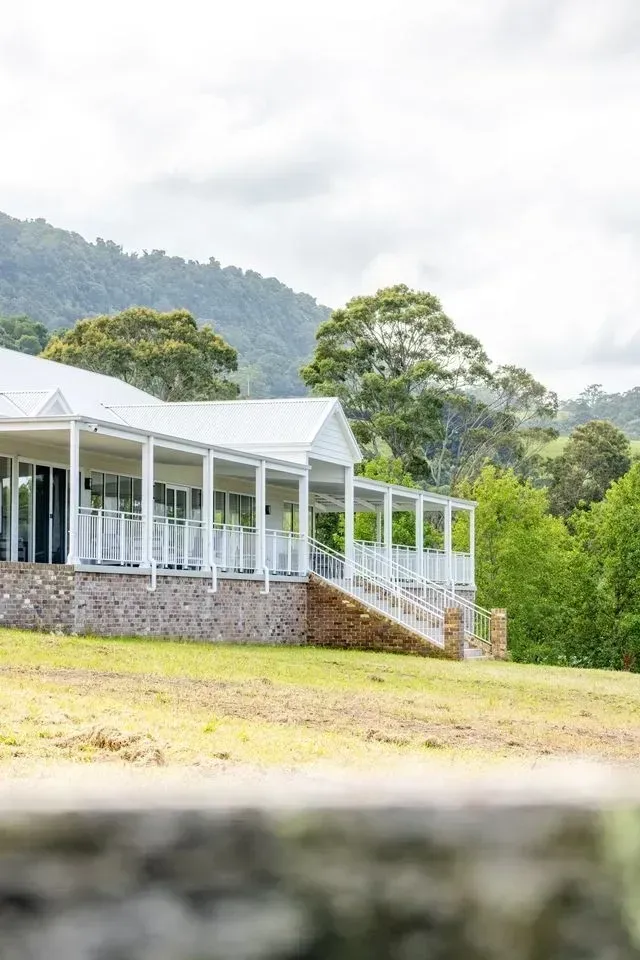 White House With a Wraparound Porch, Stone Foundation, and Green Lawn — Stark Building & Constructions In Berry, NSW