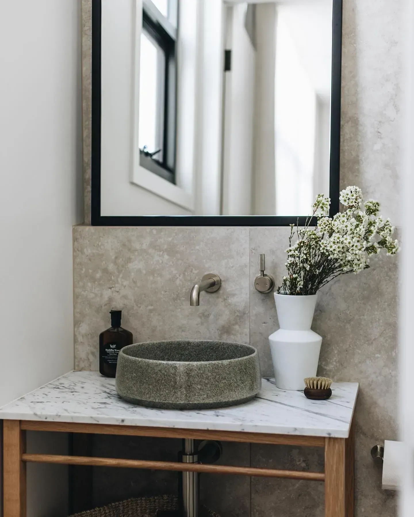 A Bathroom With a Stone Sink, White Flowers in a Vase, and a Black-framed Mirror — Stark Building & Constructions In Berry, NSW