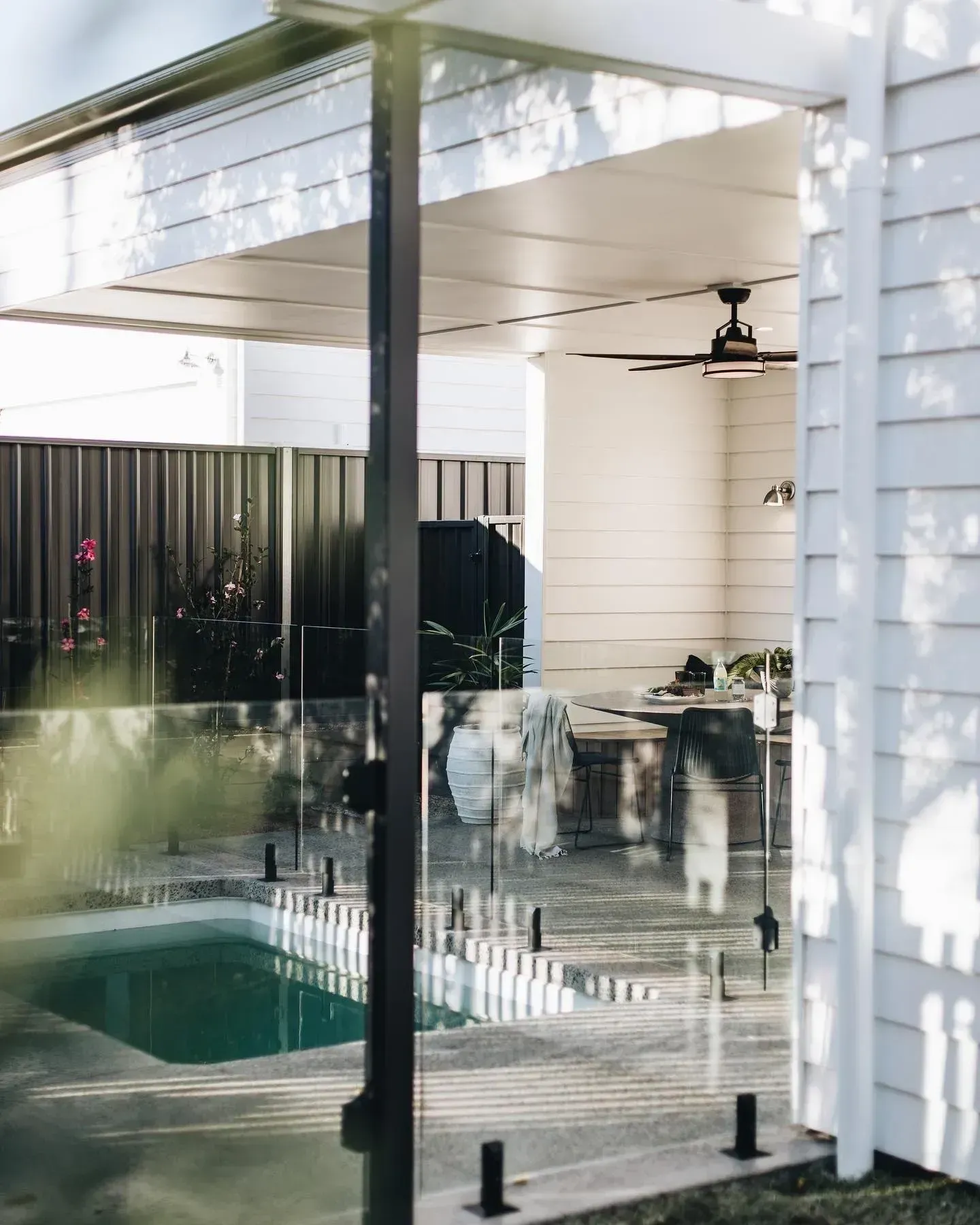 A Backyard With a Pool, White Patio, and Black Fence — Stark Building & Constructions In Berry, NSW
