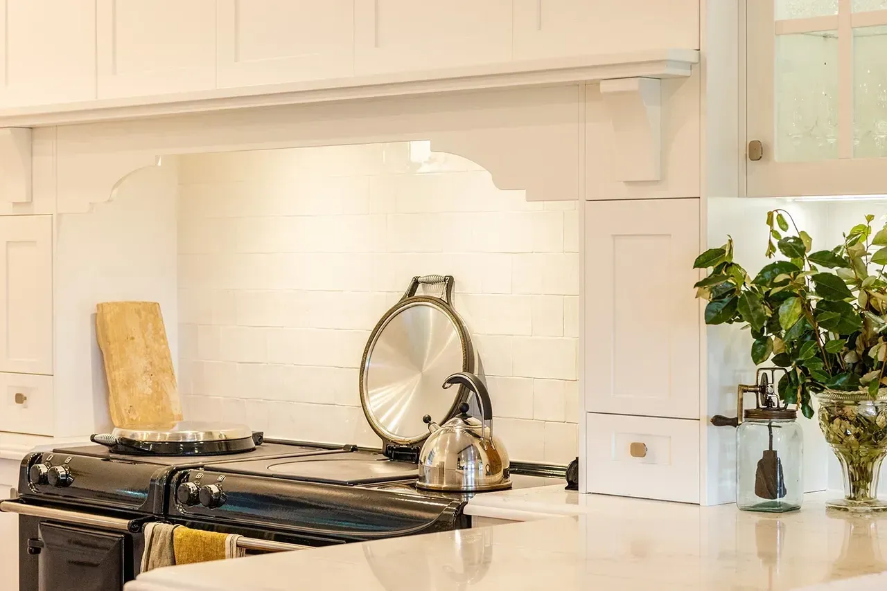 Kitchen with white cabinets, black stove, and silver kettle on a countertop — Stark Building & Constructions In Gerringong, NSW
