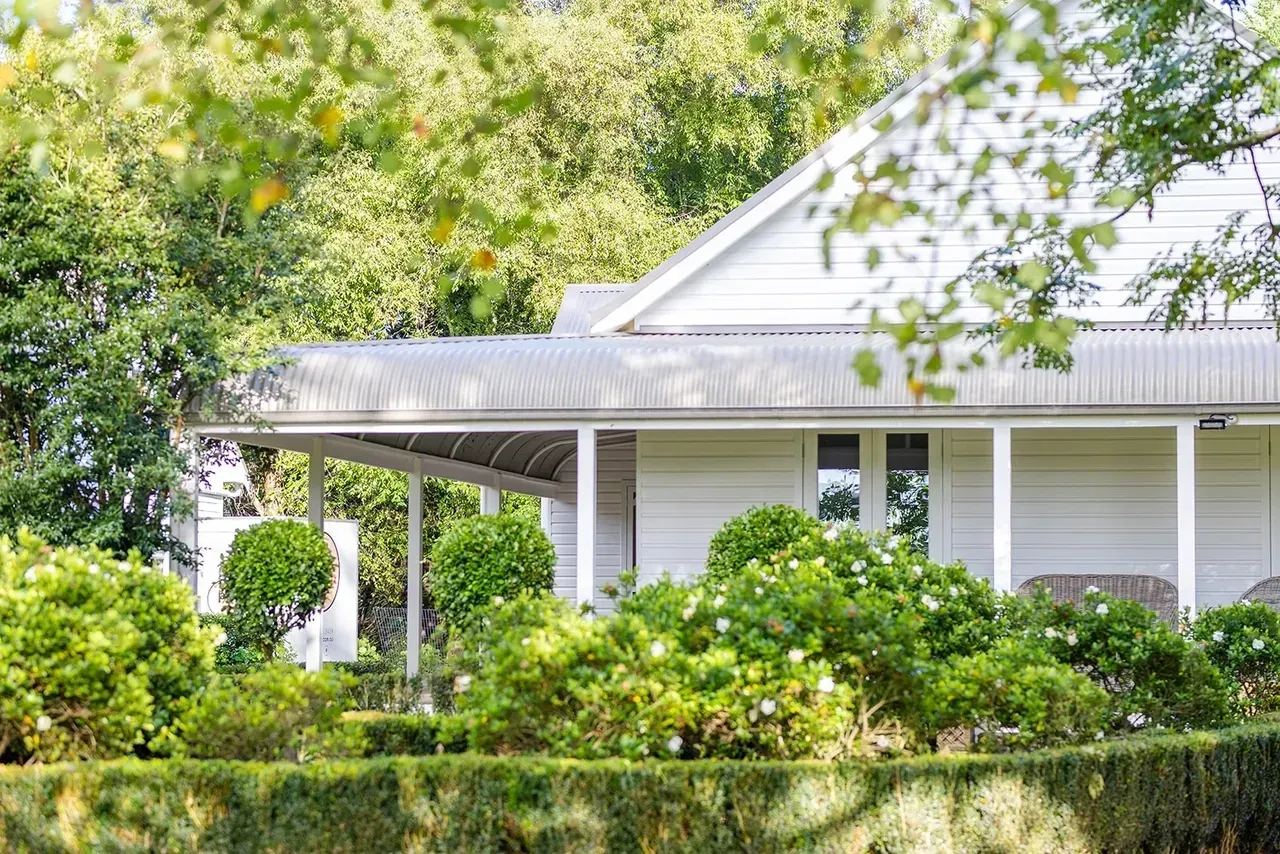 White House With Covered Porch, Surrounded by Green Bushes and Trees — Stark Building & Constructions In Berry, NSW 
