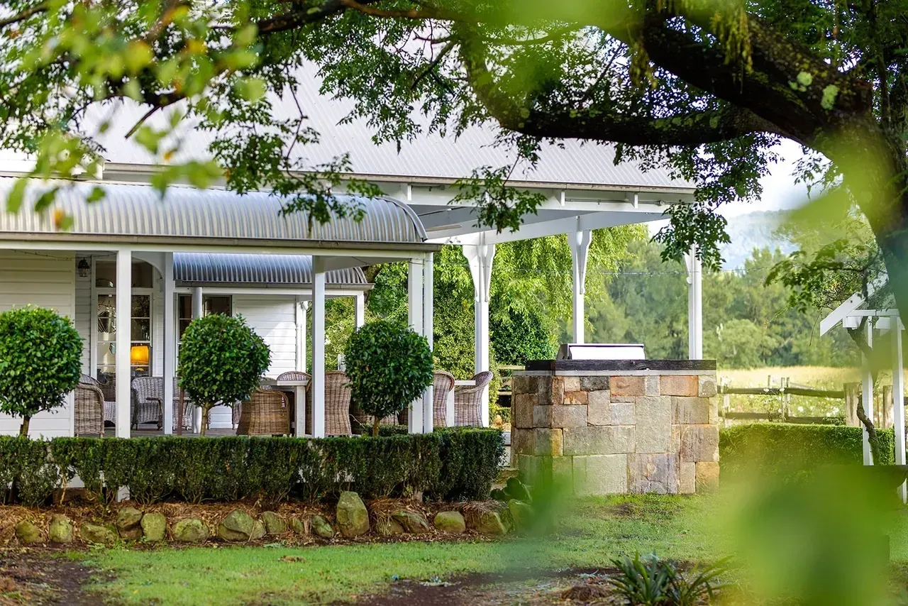 White House With Porch, Manicured Lawn, Stone BBQ, and Leafy Trees — Stark Building & Constructions In Berry, NSW 